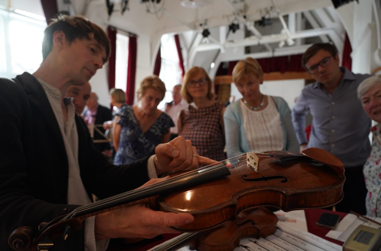 Matthew Truscott shows his violin to OAE supporters