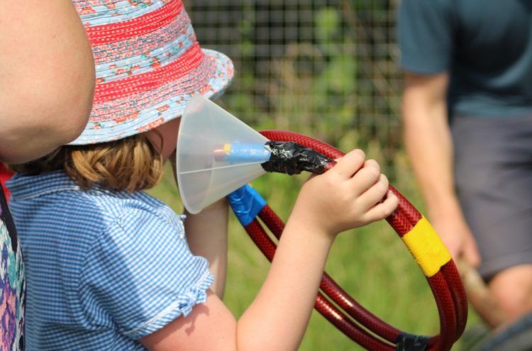 A young participant in Suffolk plays a hosepipe horn