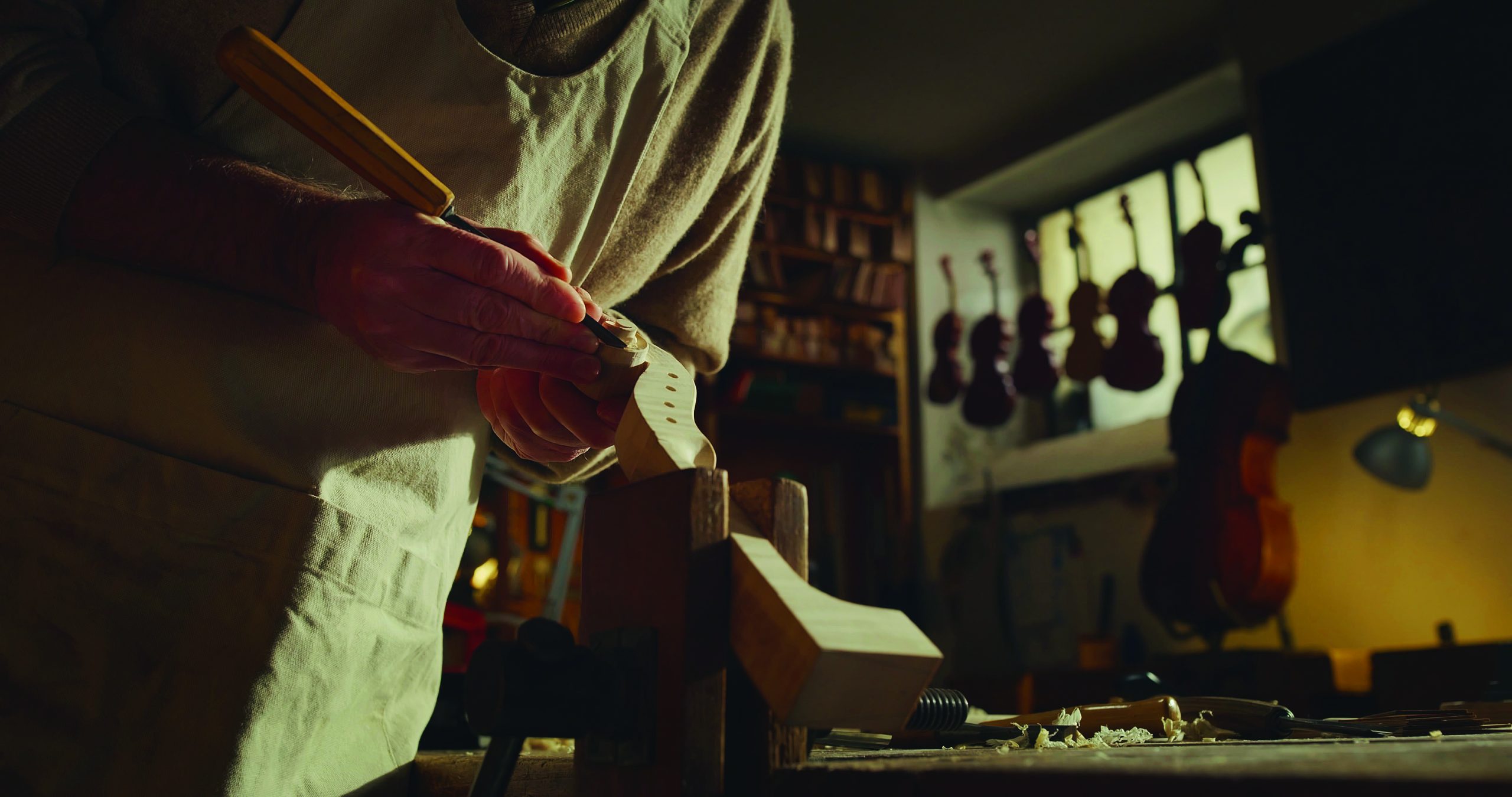 hands carving the neck of a violin